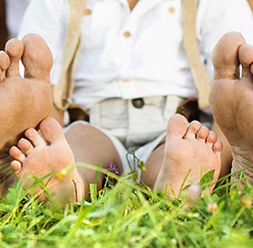 An adult and child s feet resting on grass, suggesting a moment of relaxation and family bonding.